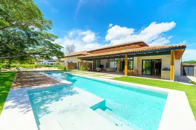 a swimming pool in front of a house at Casa Nimbu - Hacienda Pinilla in Tamarindo