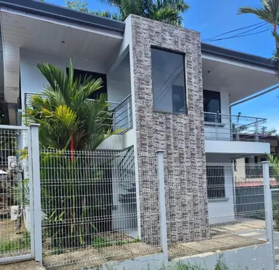 a house with a stone wall and a fence at Costa Verde Retreat 1 - Ground Floor in Quepos