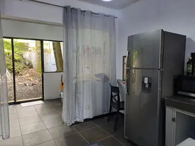 a kitchen with a refrigerator and a table at Costa Verde Retreat 1 - Ground Floor in Quepos