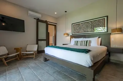 a bedroom with a large bed and a flat screen tv at Villa Ballena-luxury Ocean view in Uvita