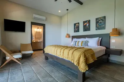 a bedroom with a bed and a tv and a chair at Villa Ballena-luxury Ocean view in Uvita