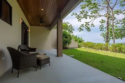 an outdoor patio with chairs and a table and grass at Villa Ballena-luxury Ocean view in Uvita