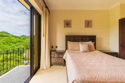 a bedroom with a bed and a balcony at Malinche 422B- Ocean view condo at Reserva Conchal in Brasilito