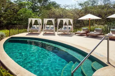 a swimming pool with chairs and umbrellas next to at Malinche 422B- Ocean view condo at Reserva Conchal in Brasilito