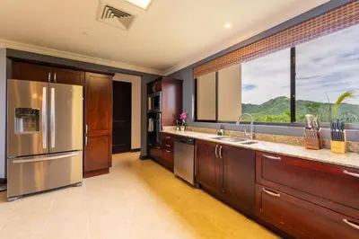 a kitchen with a stainless steel refrigerator and a large window at Malinche 422B- Ocean view condo at Reserva Conchal in Brasilito