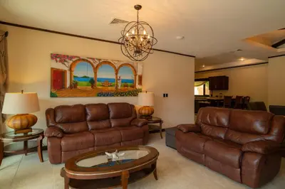 a living room with leather furniture and a chandelier at Casa Plazoleta 4 bdr private pool in Los Suenos in Herradura