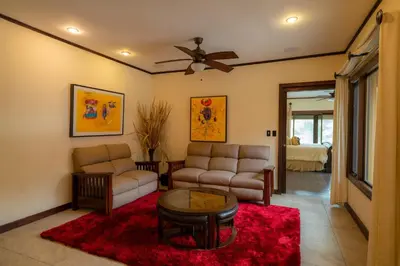 a living room with a couch and a ceiling fan at Casa Plazoleta 4 bdr private pool in Los Suenos in Herradura
