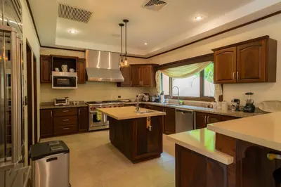 a large kitchen with wooden cabinets and a sink at Casa Plazoleta 4 bdr private pool in Los Suenos in Herradura