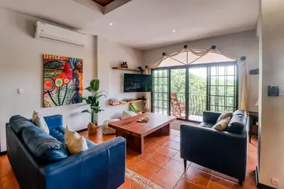 a living room with blue couches and a table at Casa Mimosa Buenavista in Playa Flamingo