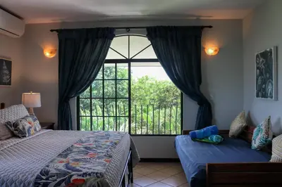 a bedroom with a bed and a large window at Casa Mimosa Buenavista in Playa Flamingo