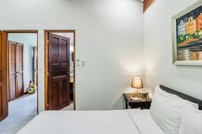 a bedroom with a white bed and a table with a lamp at Villa Sol 36 in Playa Hermosa