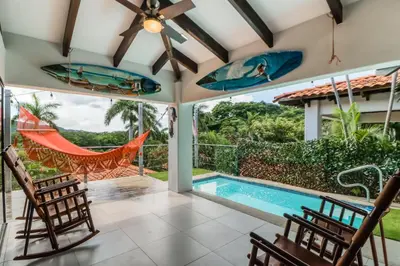 a patio with a pool and chairs and a hammock at Villa Sol 36 in Playa Hermosa