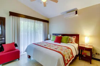a bedroom with a large bed and a red chair at The Cove 5/6 at Playa Ocotal in Ocotal
