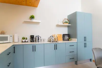 a kitchen with blue cabinets and a microwave at Sakura Haus in Turrialba