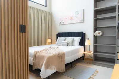 a bedroom with a bed with white sheets and pillows at Sakura Haus in Turrialba