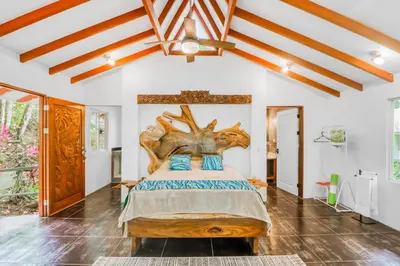 a bedroom with a large bed with a wooden headboard at Pools Bungalow at Toucan in Coronado