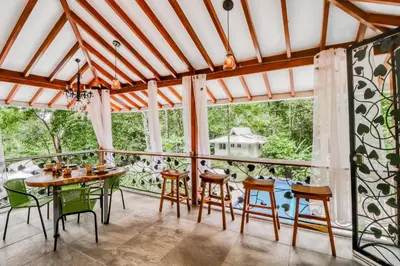 a dining room with a table and chairs and windows at Pools Bungalow at Toucan in Coronado