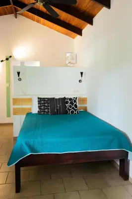 a bedroom with a bed with a green bedspread at Tortuga HBH in Playa Hermosa