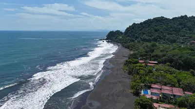 an aerial view of a black beach next to the ocean at Tortuga HBH in Playa Hermosa
