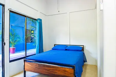 a bedroom with a bed with blue sheets and a window at Deer Apartments Bahía Ballena in Uvita