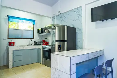 a kitchen with blue cabinets and a stainless steel refrigerator at Deer Apartments Bahía Ballena in Uvita