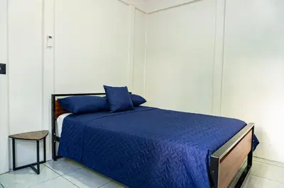a bedroom with a bed with blue sheets and a stool at Deer Apartments Bahía Ballena in Uvita