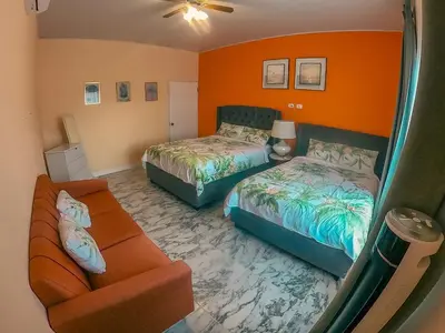 a hotel room with two beds and a couch at Vacation Home with Pool Quepos in Quepos