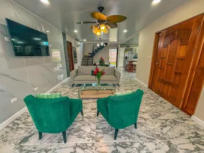a living room with a couch and two green chairs at Vacation Home with Pool Quepos in Quepos