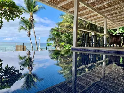 a swimming pool with palm trees and the ocean at Backyard Beach House Oceanfront Luxury 5 Bdr in Playa Hermosa