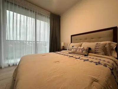 a bedroom with a large bed with a large window at Modern Condo in Núcleo La Sabana with Pool in San José