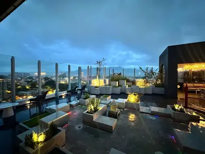 a rooftop patio with a view of the city at night at Modern Condo in Núcleo La Sabana with Pool in San José