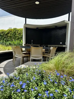 a patio with chairs and a table and some blue flowers at Modern Condo in Núcleo La Sabana with Pool in San José