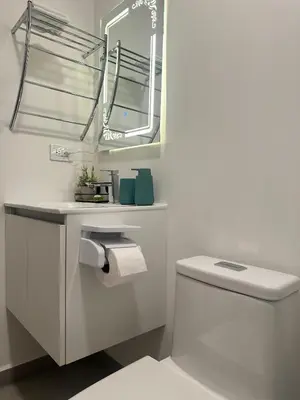 a white bathroom with a toilet and a mirror at Modern Condo in Núcleo La Sabana with Pool in San José