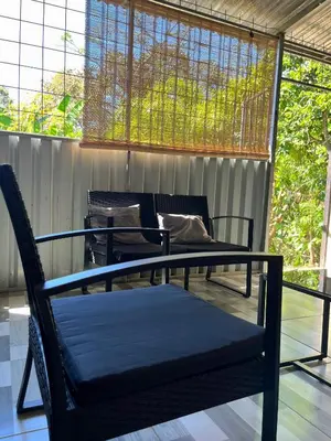a porch with two chairs and a bed and a window at La Casa de Tita in Orotina