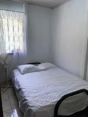 a white bed in a room with a window at La Casa de Tita in Orotina
