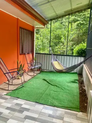 a porch with a hammock and chairs on a patio at La Casa de Tita in Orotina