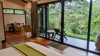 a bedroom with a large window and a table and chairs at Olingo Monteverde - Studio Apartment with Jacuzzi in Monteverde Costa Rica