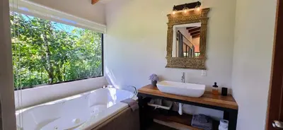 a bathroom with a tub and a sink and a mirror at Olingo Monteverde - Studio Apartment with Jacuzzi in Monteverde Costa Rica