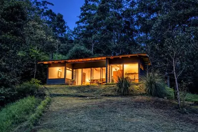a small house in the woods at night at Olingo Monteverde - Studio Apartment with Jacuzzi in Monteverde Costa Rica