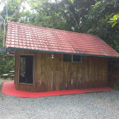 a small building with a red floor and a roof at La Ceiba Ecoadventures Wildlife Reserve in Platanillo