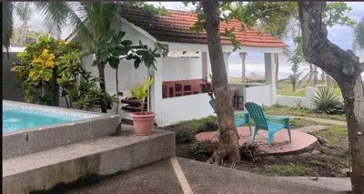 a house with a blue chair next to a swimming pool at Beachfront Paradise in Tivives, Costa Rica - Your Home Away from Home in Tivives