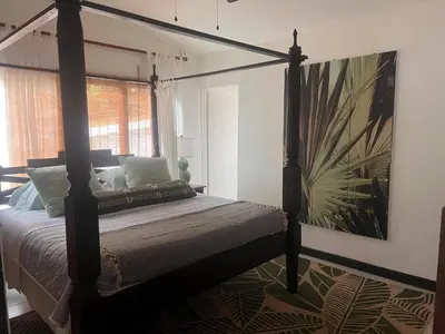 a bedroom with a four poster bed with a painting on the wall at Beachfront Paradise in Tivives, Costa Rica - Your Home Away from Home in Tivives