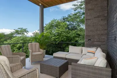 a patio with wicker chairs and a couch and tables at Beach Mode Luxury 3-Story House in Tamarindo in Tamarindo