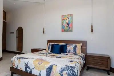 a bedroom with a large bed with blue pillows at Beach Mode Luxury 3-Story House in Tamarindo in Tamarindo