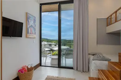 a living room with a sliding glass door to a balcony at Beach Mode Luxury 3-Story House in Tamarindo in Tamarindo