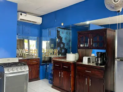 a kitchen with blue walls and wooden cabinets at Beach Studio for 4 - AC - WiFi - Parking Santa Teresa in Santa Teresa