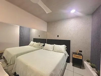 a bedroom with two beds with white sheets at Ken lower apartment in Quepos