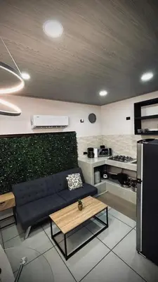 a living room with a couch and a kitchen at Ken lower apartment in Quepos