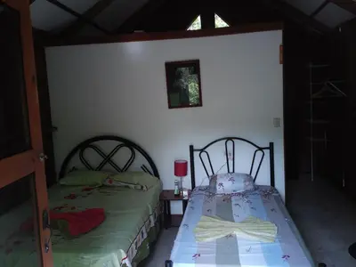 a bedroom with two beds and a table with a lamp at La Ceiba Ecoadventures Refugio de vida silvestre in Platanillo