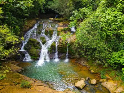 a waterfall in the middle of a pool of water at La Ceiba Ecoadventures Refugio de vida silvestre in Platanillo